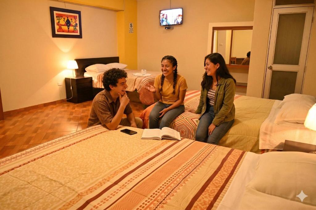 a group of three people sitting on a bed at Hotel Bartol in Huancayo