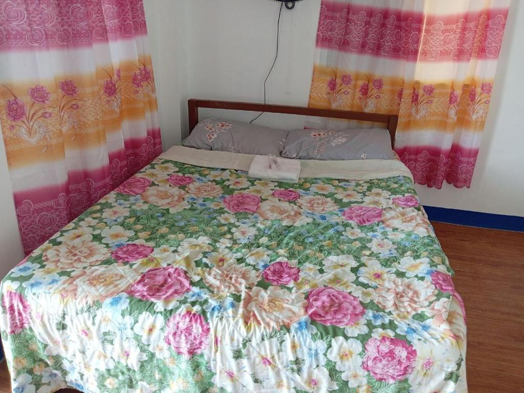 a bed with a floral comforter in a bedroom at RENDER VOUS A'l MER in Puerto Princesa City