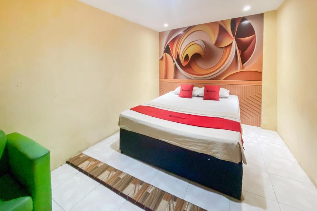 a bedroom with a bed with a painting on the wall at RedDoorz at Hotel Warna Palopo in Palopo