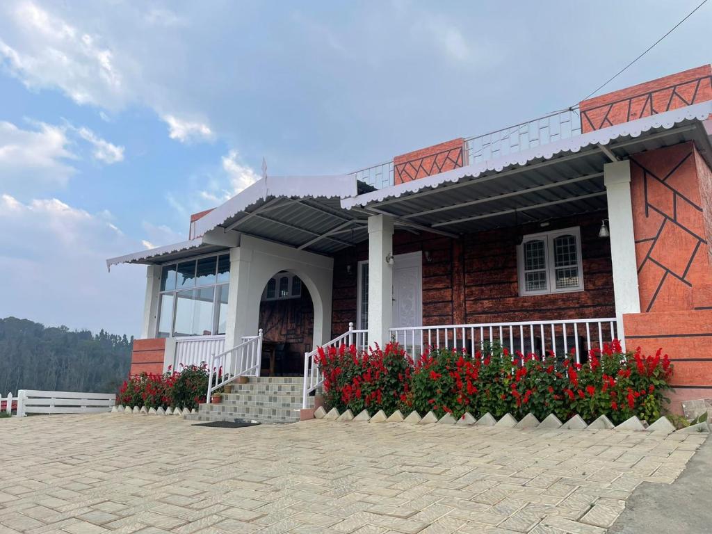 a brick building with red flowers in front of it at Sky High Villa - Ooty in Ooty