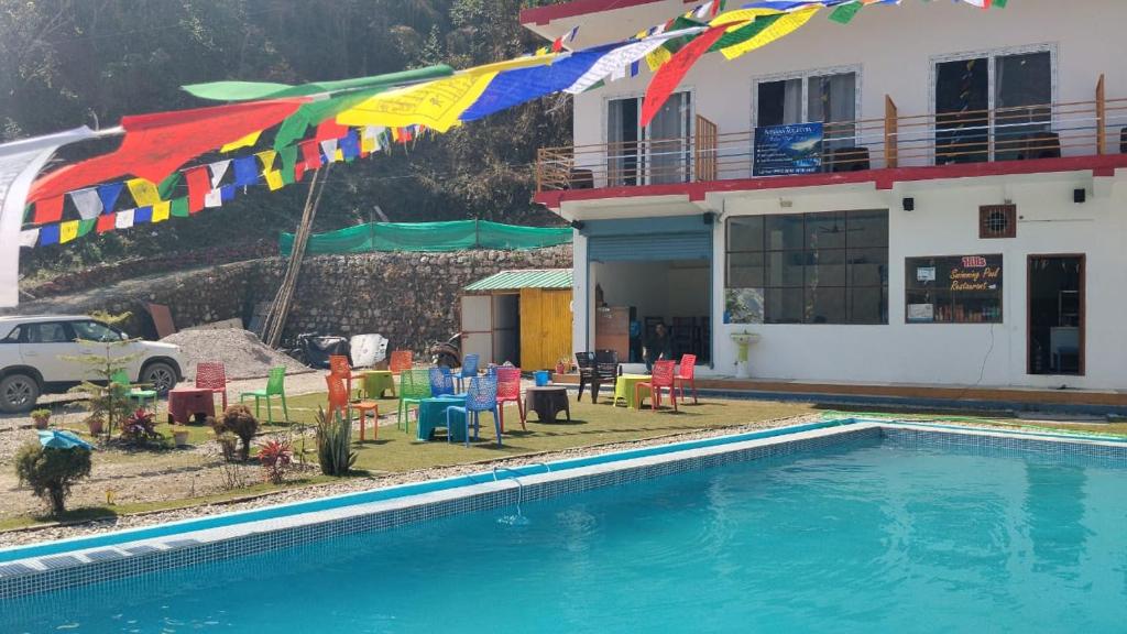 a pool with chairs and umbrellas next to a building at Nirvana Maldevta in Dehradun