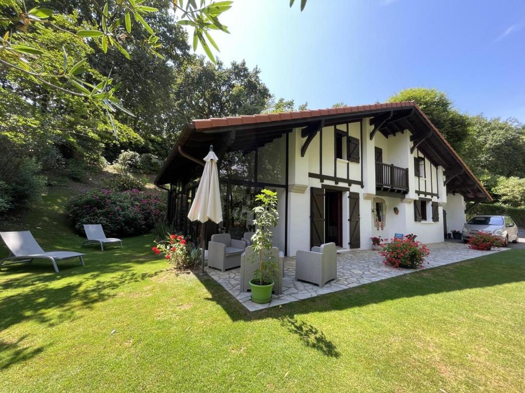 a house with an umbrella and chairs and a lawn at Chez garcia in Urrugne