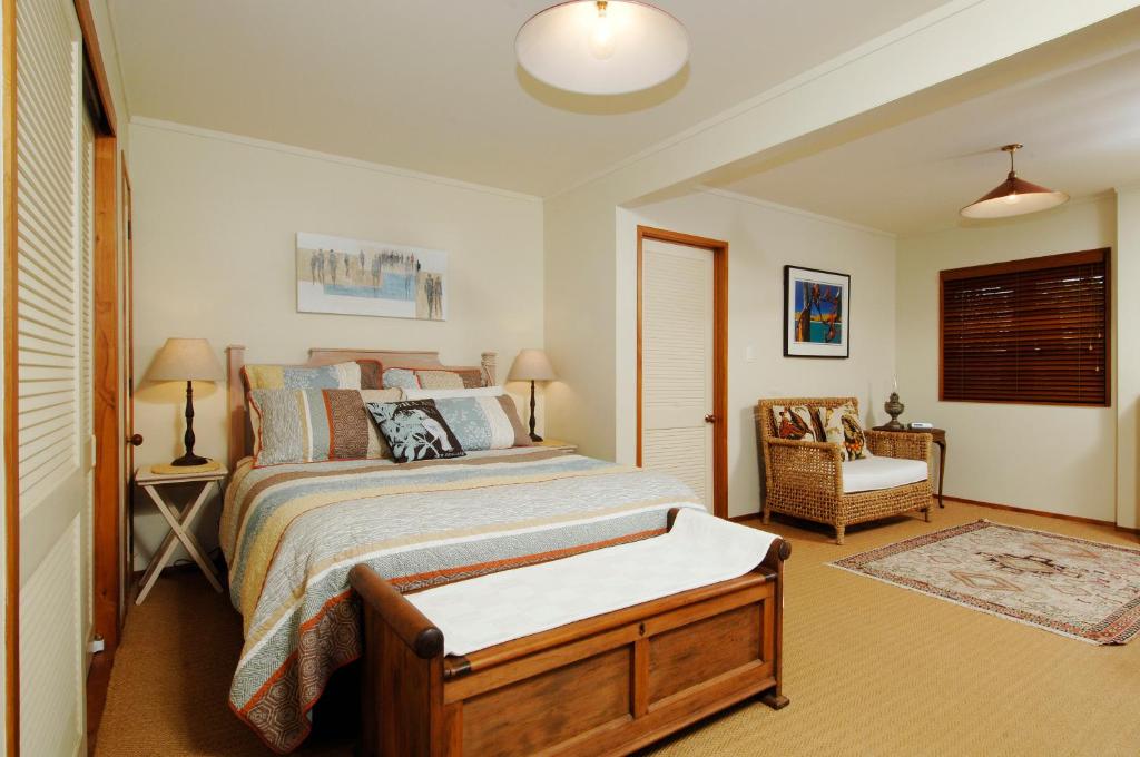 1 dormitorio con 1 cama y 1 silla en Orewa Beachside, en Orewa