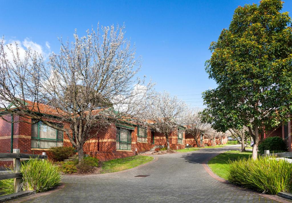 uma casa de tijolos com uma árvore e uma rua em Mount Waverley Townhouses em Mount Waverley