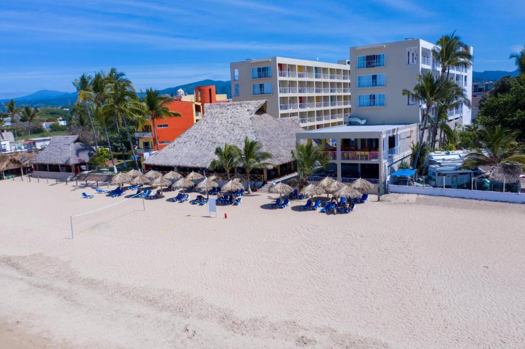 a beach with chairs and umbrellas and a hotel at Decameron Isla Coral Guayabitos, Ramada All-Inclusive Resort in Rincon de Guayabitos