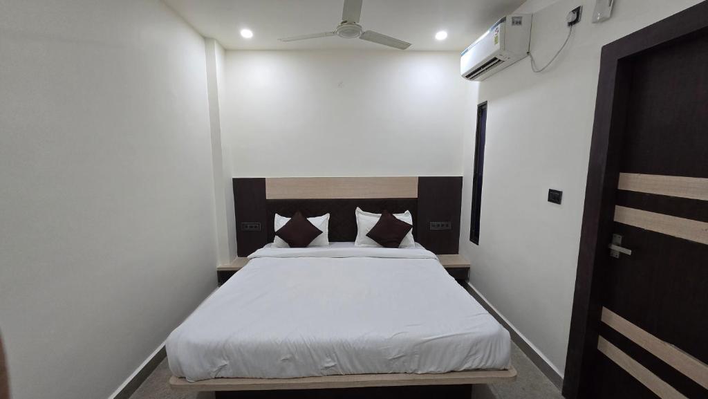 a small bedroom with a bed with white sheets at SHRI DIVYAM Hotel & Restaurant in Bhopal