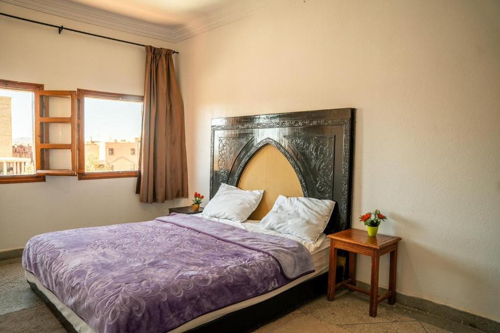 a bedroom with a bed with a purple comforter at Hostel Assafar in Ouarzazate