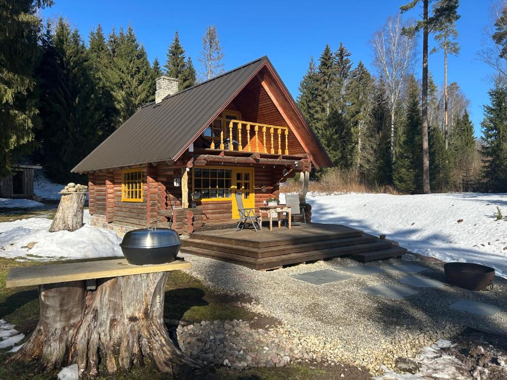 a log cabin with a deck in the snow at Ala-Kure metsamaja in Varbuse