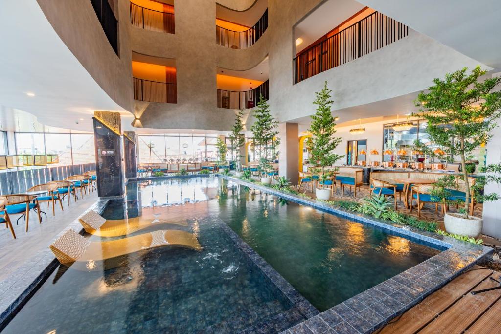 an indoor pool in a building with tables and chairs at Azana Boutique Hotel Solo in Purwosari