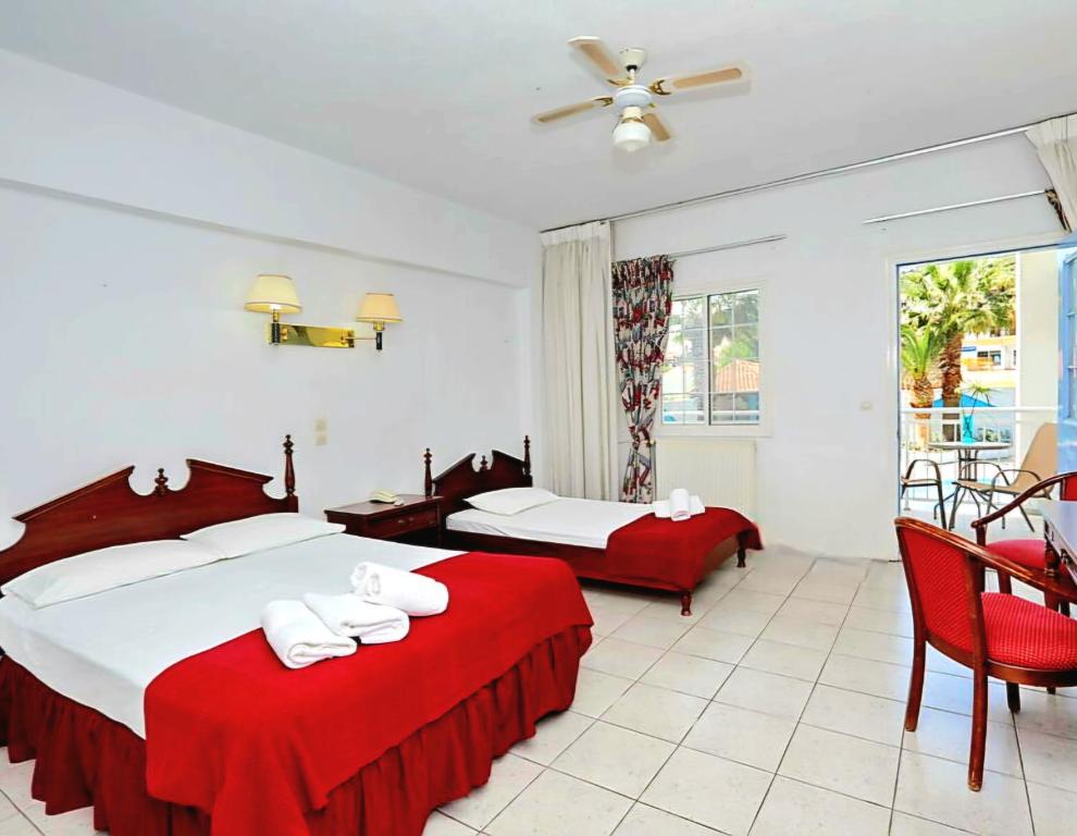 a hotel room with two beds with red sheets at Dolphin Hotel in Skopelos Town
