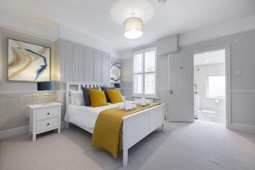 a bedroom with a bed with yellow pillows and a bathroom at Stunning 5 Bed Regency Home in Gloucestershire