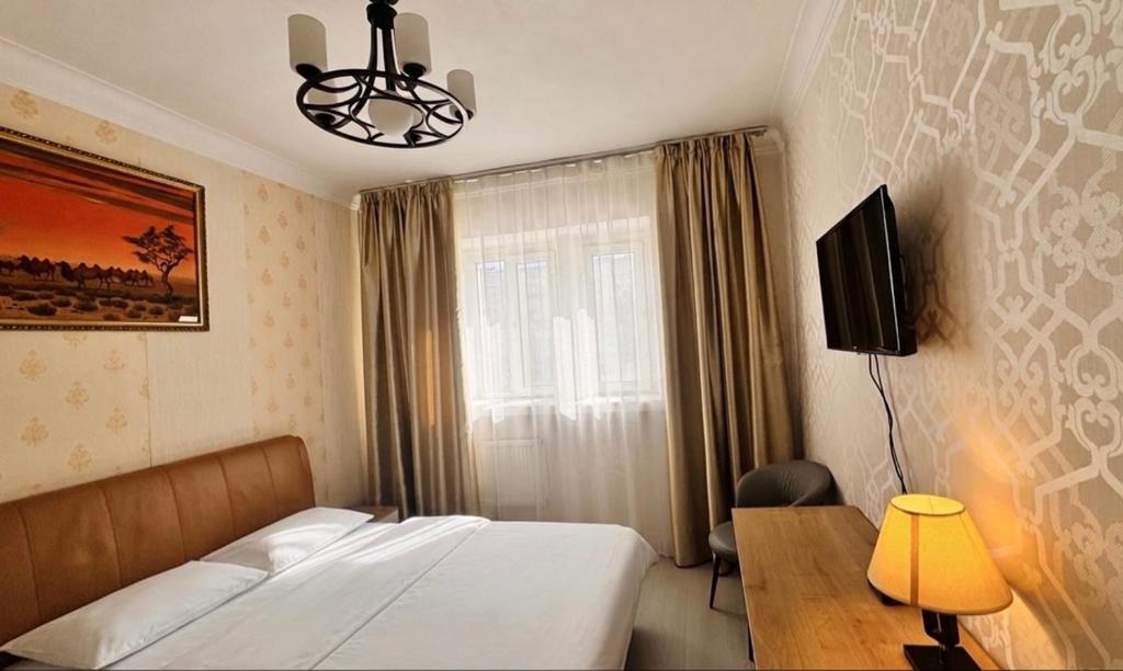 a bedroom with a bed and a desk and a television at Khongor Guest house & Tours in Ulaanbaatar