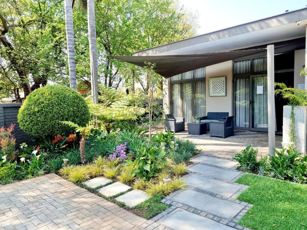 a garden with a patio and a house at Glen Maine Guest House in Pretoria