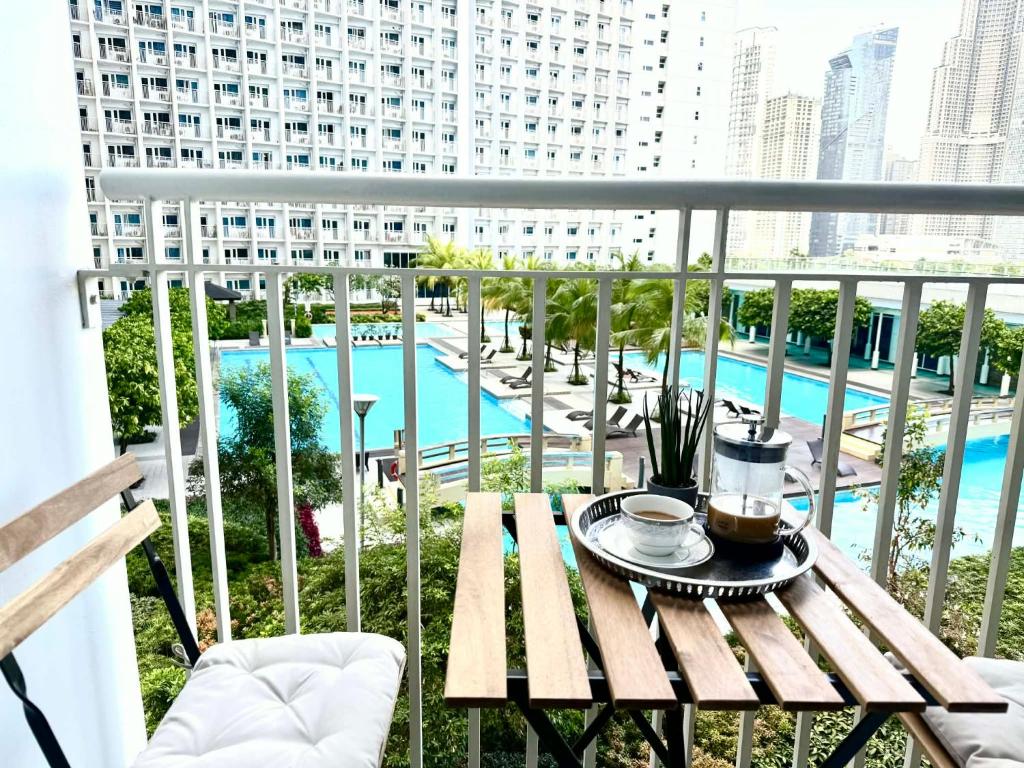a table on a balcony with a view of a pool at Modern Stays Makati Pool View Jazz Residences in Manila