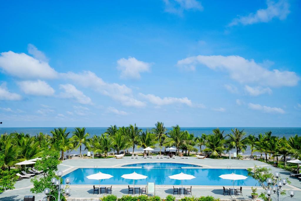 an overhead view of a pool with umbrellas and the ocean at Hải Tiến Resort in Mỹ Ðuc