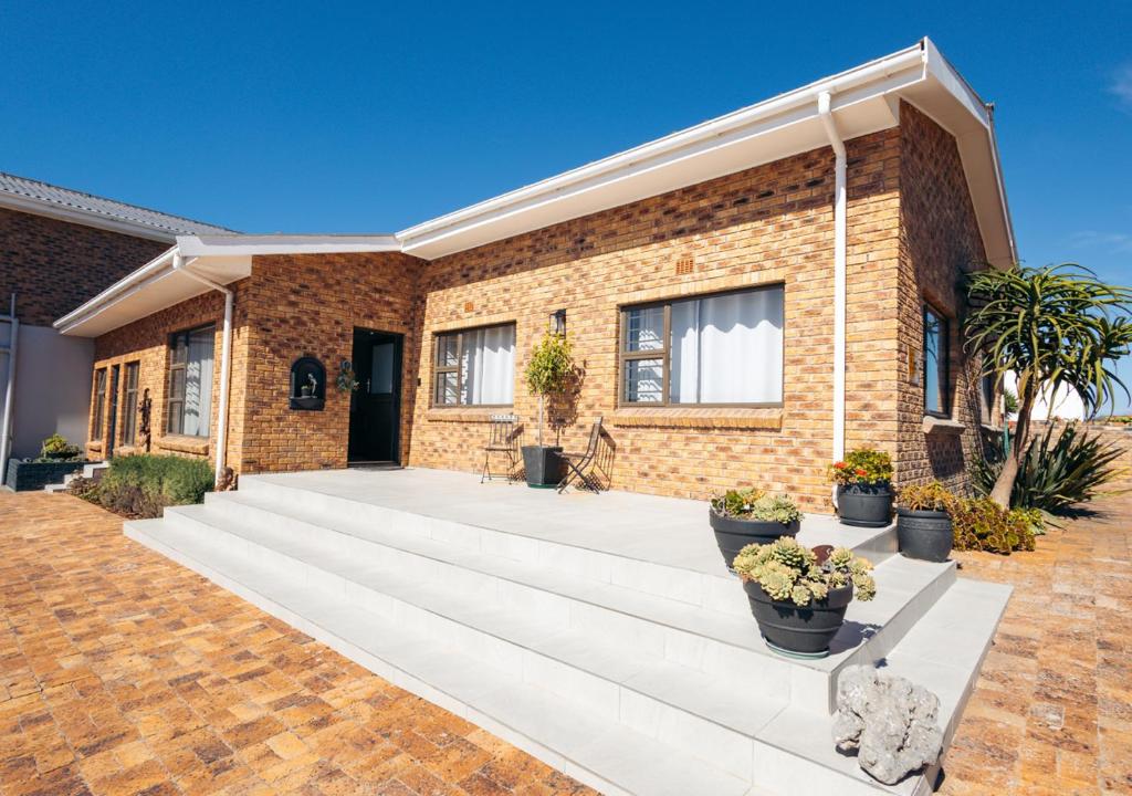 a brick house with potted plants in front of it at AllesWells in Yzerfontein