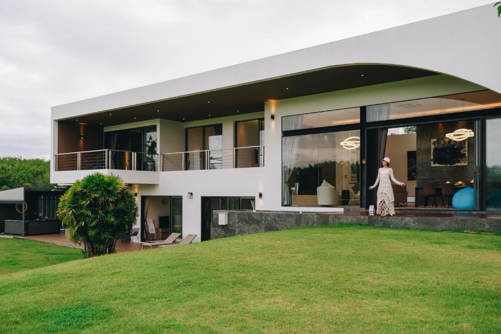 a woman is standing in front of a house at Porsampao Luxury Villa in Ban Khok Khilek