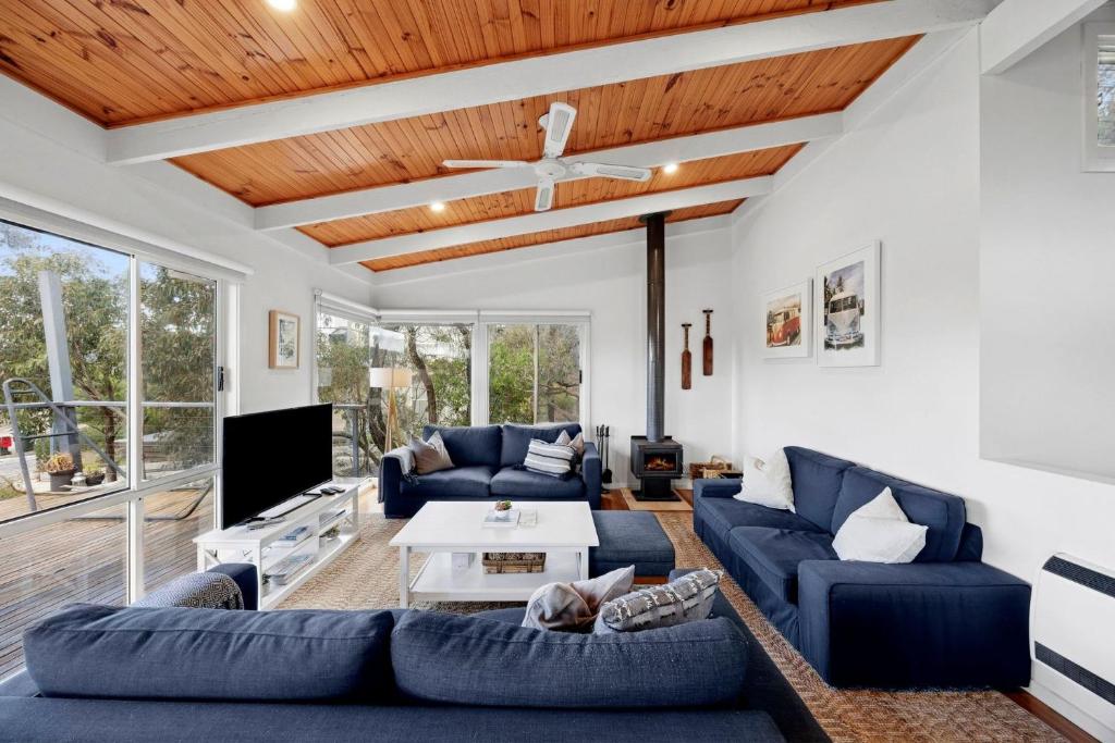 a living room with blue couches and a wooden ceiling at Salty Haven in Moggs Creek