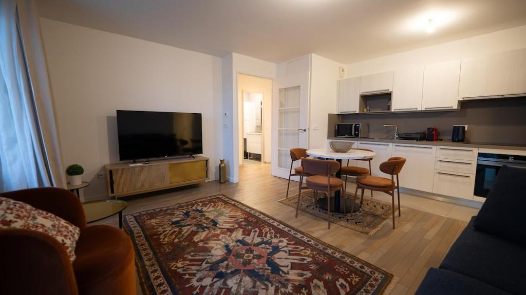 a living room with a kitchen and a table with chairs at Sky Two La Defense in Courbevoie
