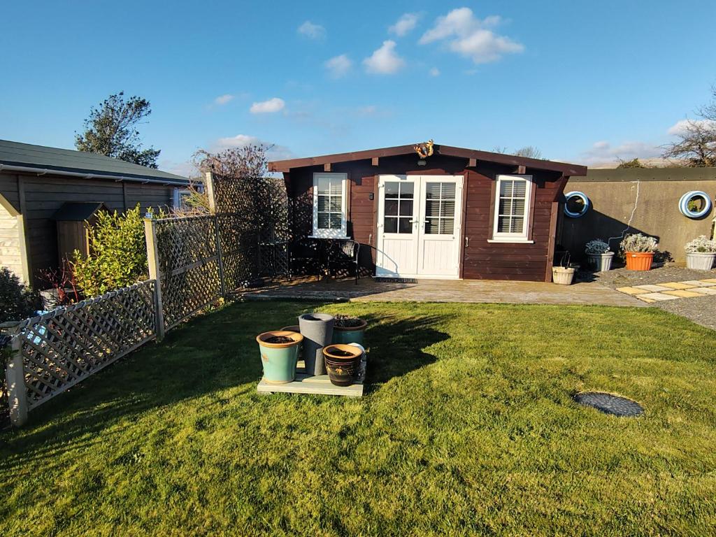 a house with a yard with two pots in the grass at Butterfly Cabin in Millom