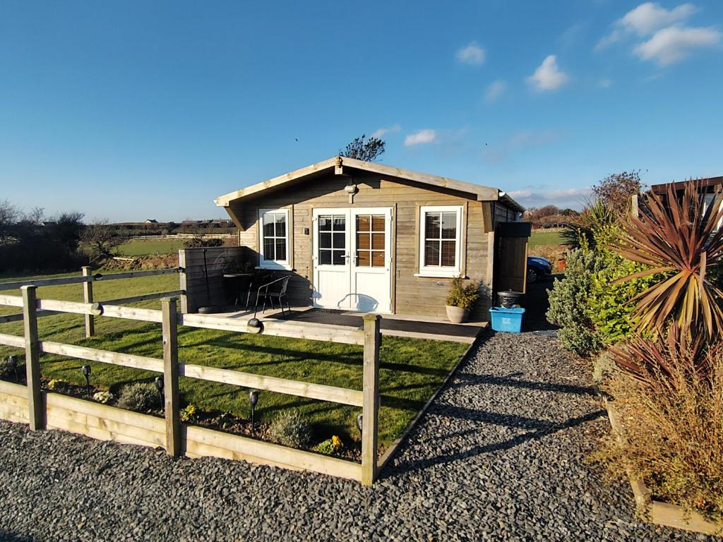 a tiny house with a fence in front of it at Bumble Bee Cabin in Bootle
