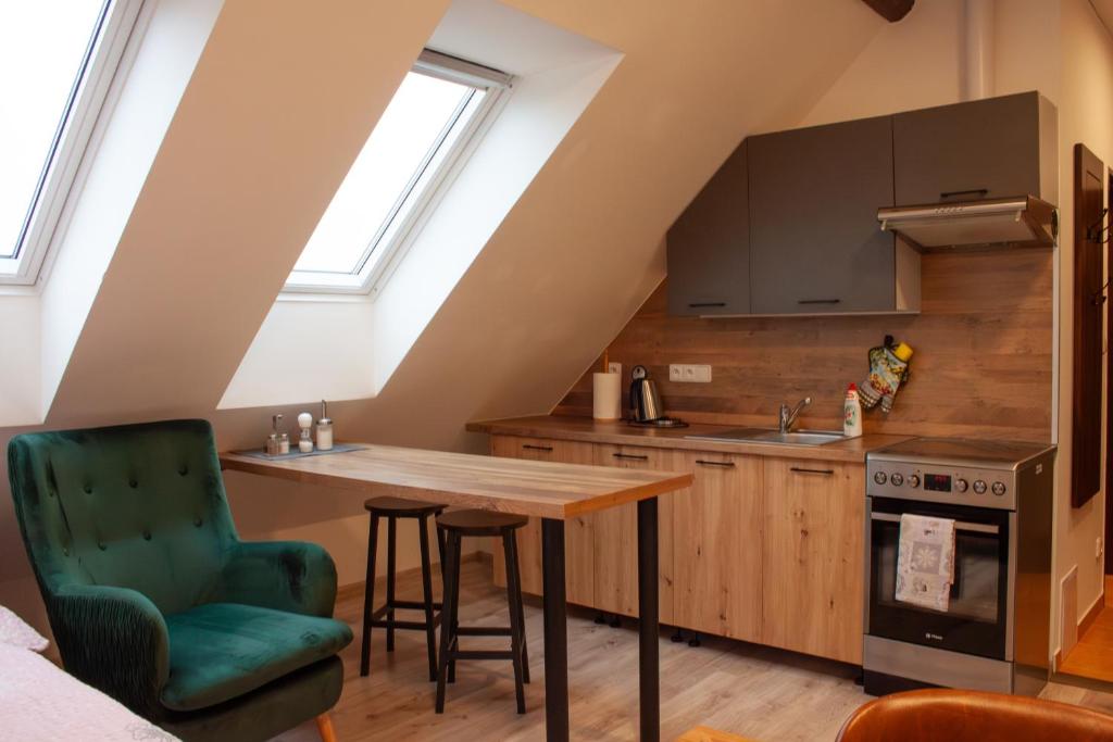 a kitchen with a wooden table and a green chair at Ubytování 1kk ve Zlonicích in Slaný