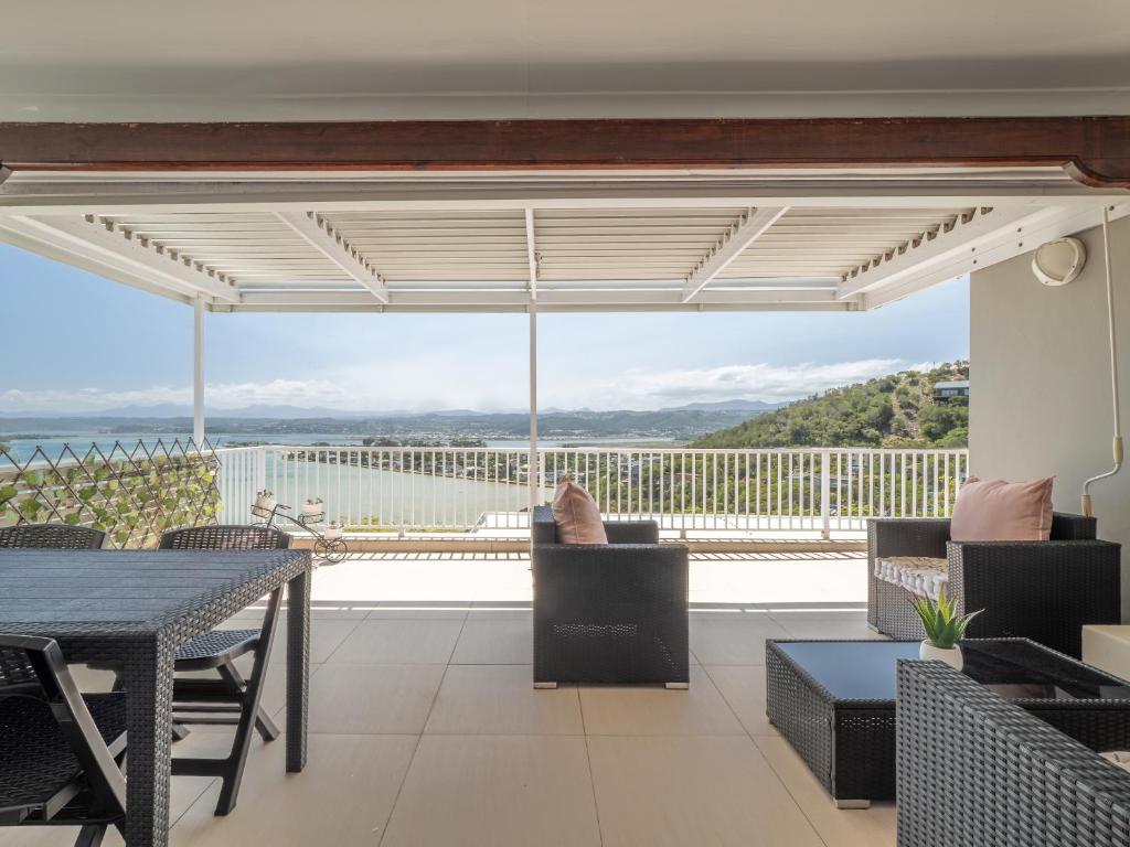 a balcony with a table and chairs and a large window at Coney Glen Penthouse in Knysna