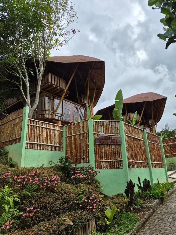 a house with two roofs on a green fence at Villa Bambu Juma & Bakal in Kotasuka