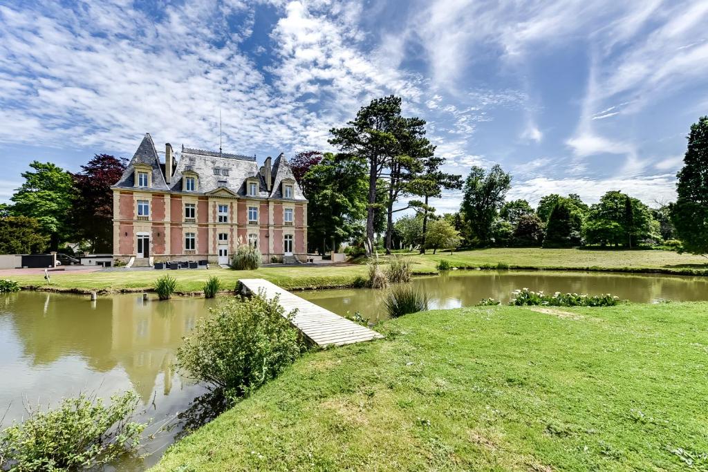 an old house with a bridge in front of a pond at Château Côte de Nacre in Ver-sur-Mer