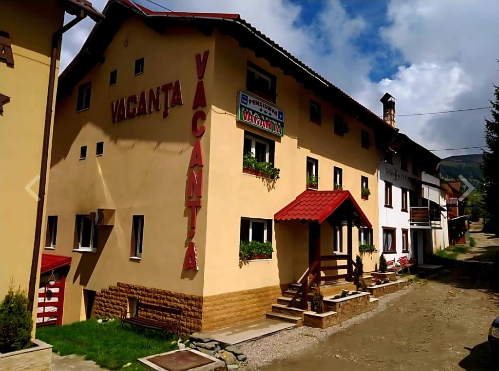 a building with a sign on the side of it at Pensiunea Vacanta in Straja