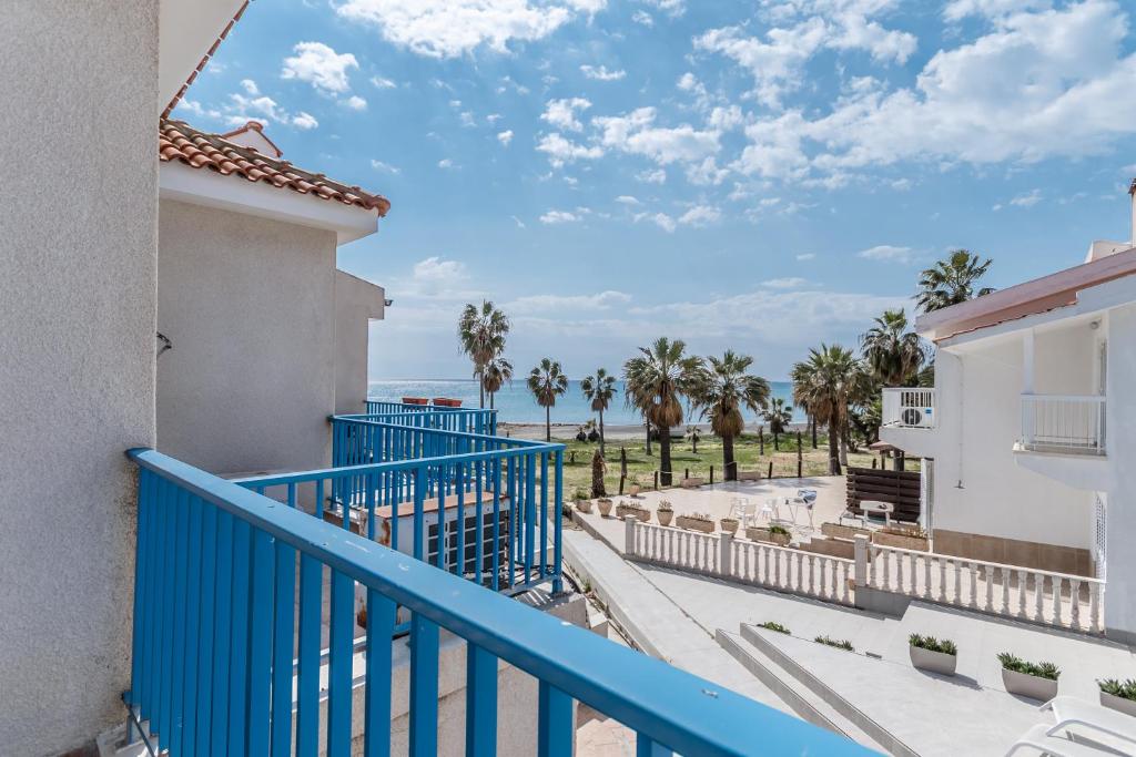 a balcony with a blue railing and palm trees at Beach Escape Beachfront Apartment in Pyla