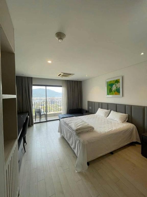 a bedroom with a large bed and a balcony at Golden Bay Danang in Danang