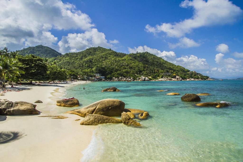 a beach with rocks and the ocean and mountains at Crystal Bay Yacht Club Beach Resort in Lamai