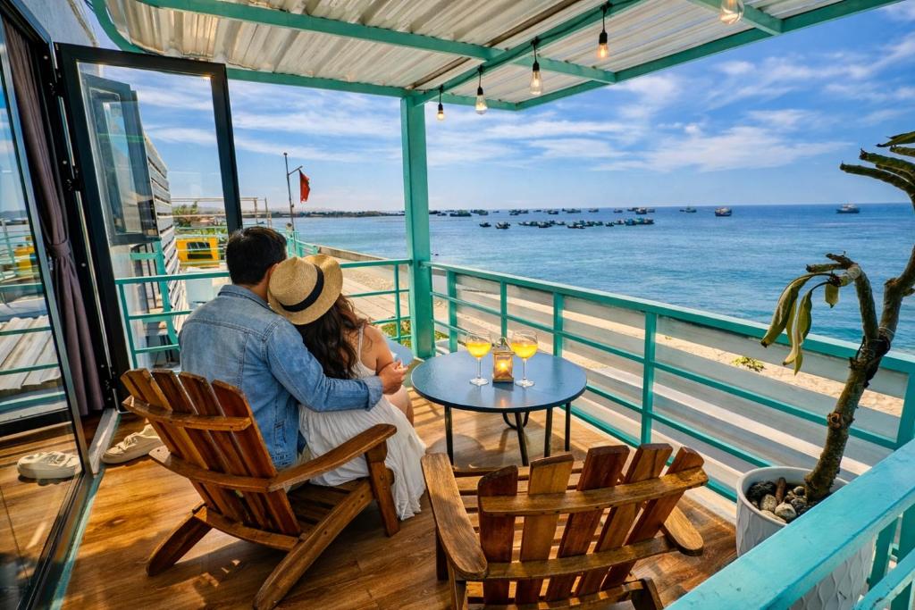 a man and a woman sitting at a table on a balcony overlooking the ocean at Villa Đại Dương 2 View biển in Cu Lao Thu