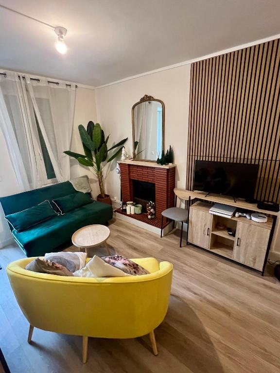 a living room with a yellow couch and a tv at Maison de la Gour MELLE in Melle