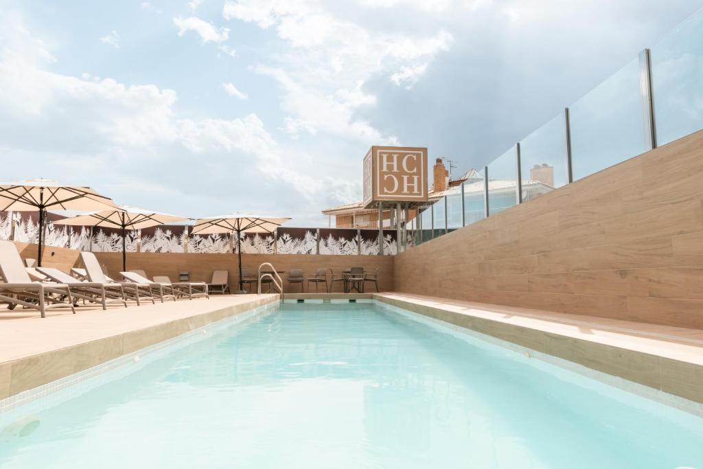 a swimming pool with chairs and a hotel sign at Hotel Andalucía Center in Granada