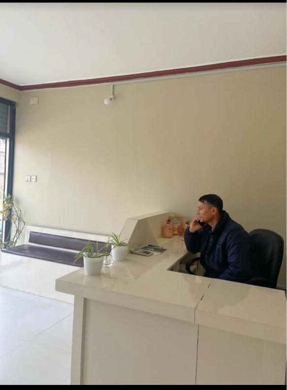 a man sitting at a desk talking on a cell phone at Hotel Lake Heaven in Deorāli