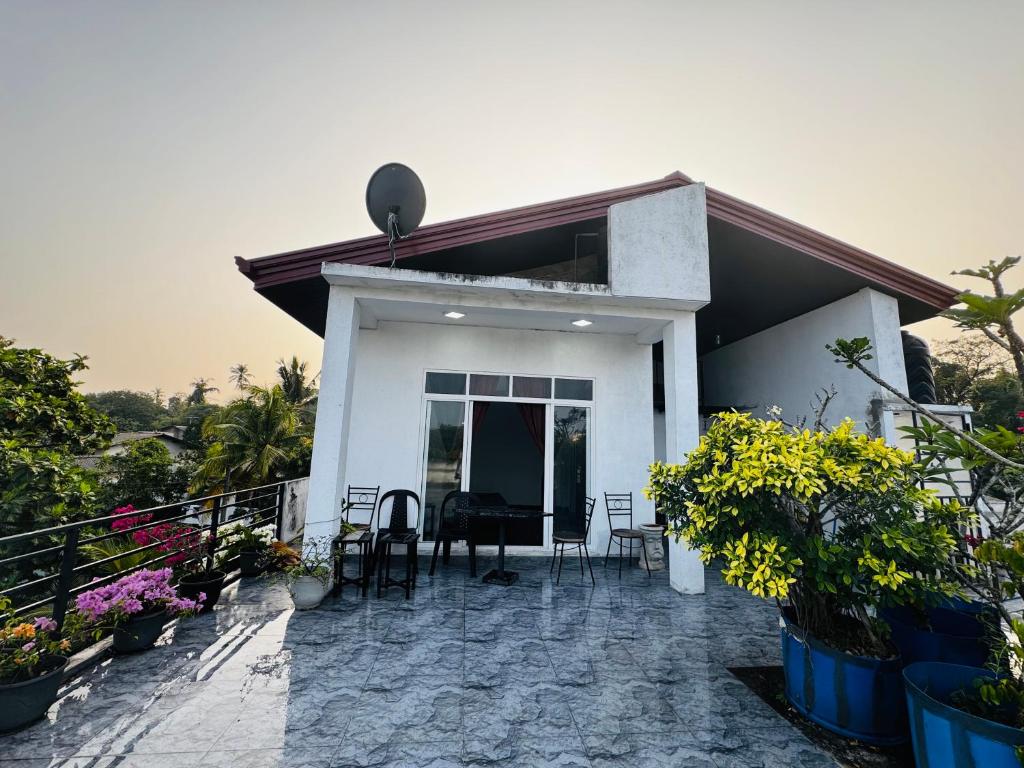 a white house with a patio with chairs and plants at 22 apartments in Kalapaluwawa
