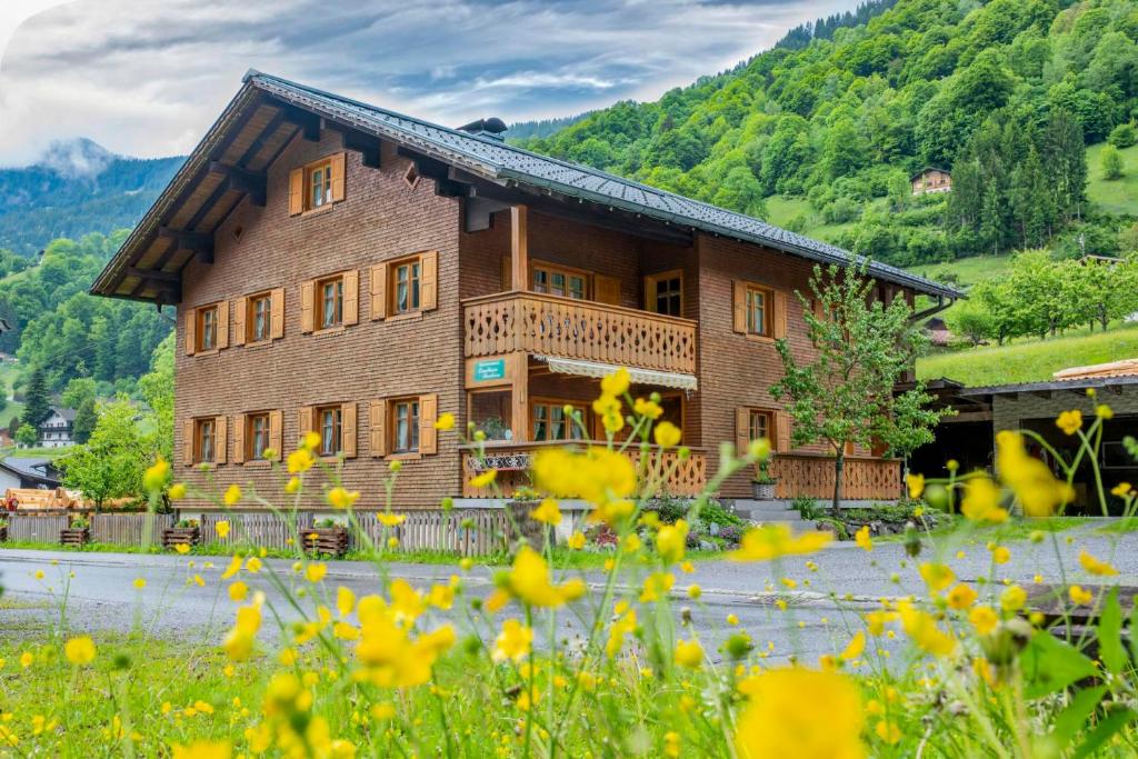 a large wooden house in a field of flowers at Landhaus Barbara in Silbertal