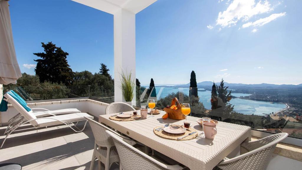 a table and chairs on a balcony with a view at Villa Filothea with Jacuzzi & SV by CorfuEscapes in Spartýlas