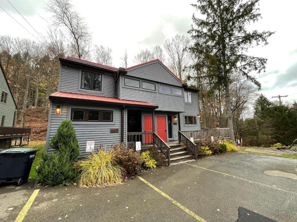 a gray house with a red door in a parking lot at Mountain bike Ski Eville Mecca in Ellicottville