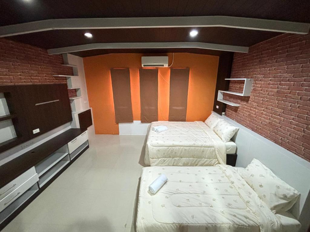 a room with two beds and a brick wall at Anchan Home Stay Hatyai in Hat Yai