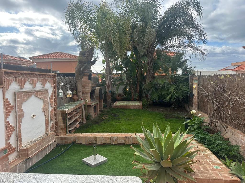 a backyard with a yard with a palm tree at Dúplex con vistas panorámicas in Calabardina