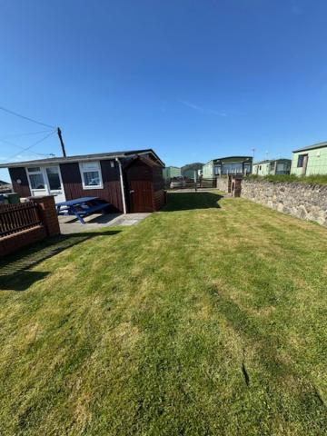 a grassy yard with a house in the background at Caban Caru 2 in Tywyn