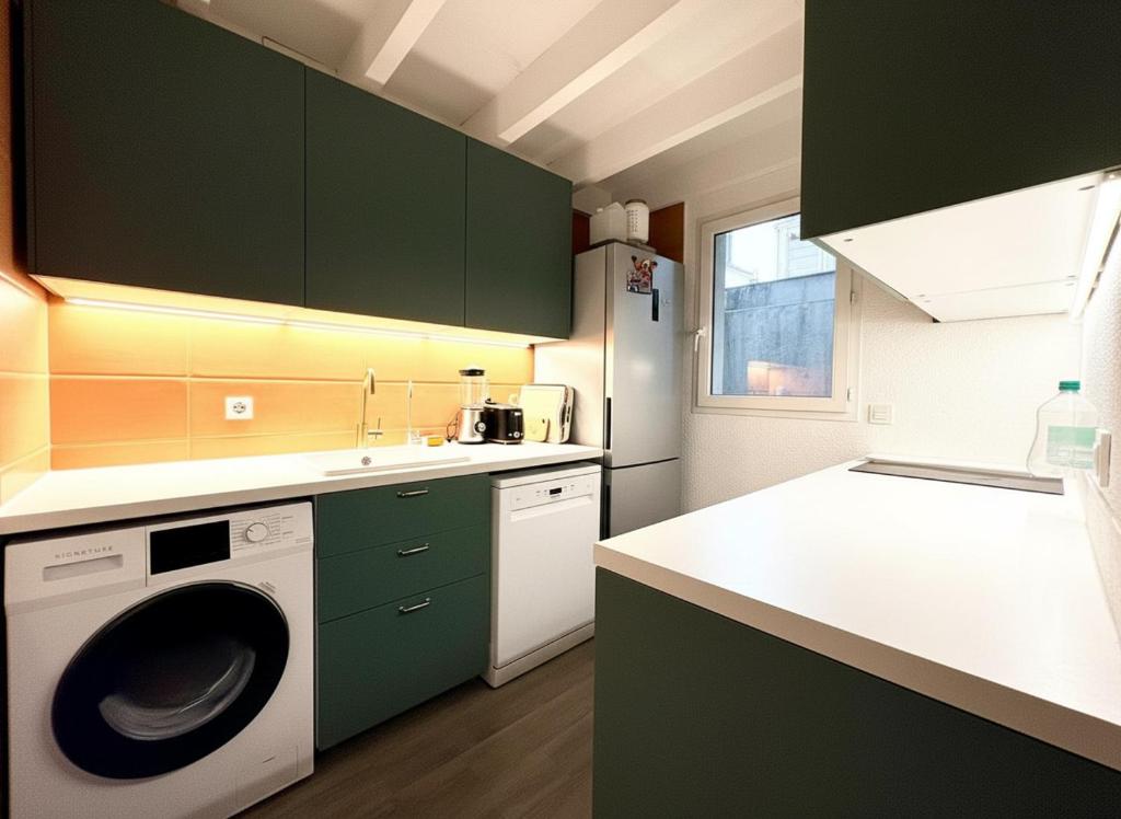 a kitchen with green cabinets and a washing machine at Les Embruns de Tarnos in Tarnos