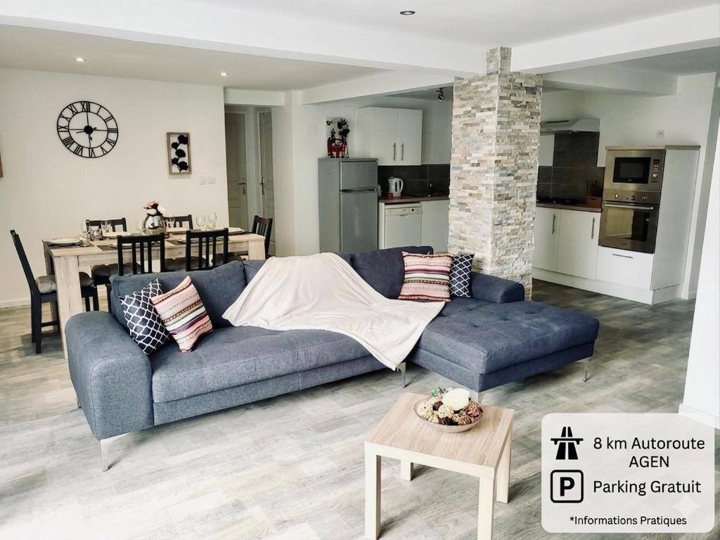 a living room with a blue couch and a kitchen at - Loft fléchette - clim - garage in Laplume