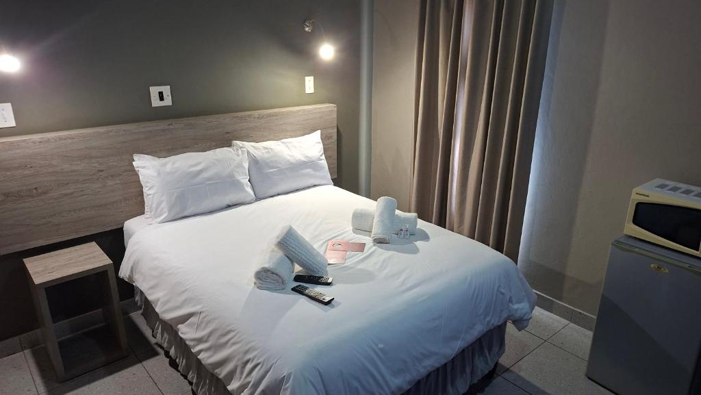 a hotel room with a large bed with white sheets at Postmasburg Inn in Postmasburg