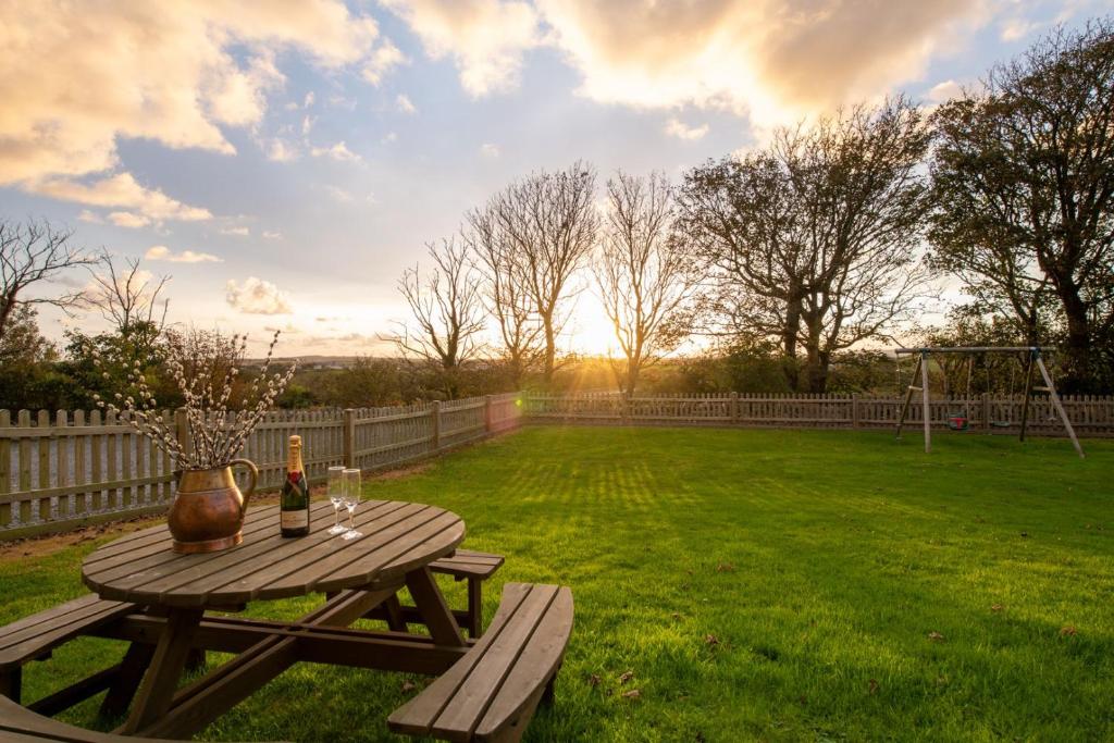 a picnic table with a bottle of wine on a lawn at Bryn Lon Bach in Caeʼr-geiliog