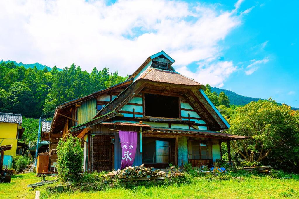 an old house sitting in a field with trees at 淵明庵 in Fujikawa