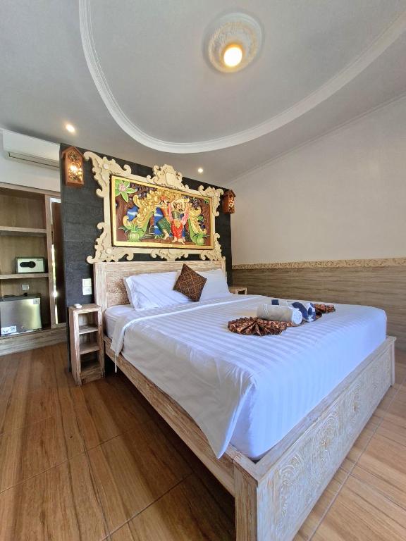 a bedroom with a large bed with a painting on the wall at Mikuk Cottages Canggu in Canggu